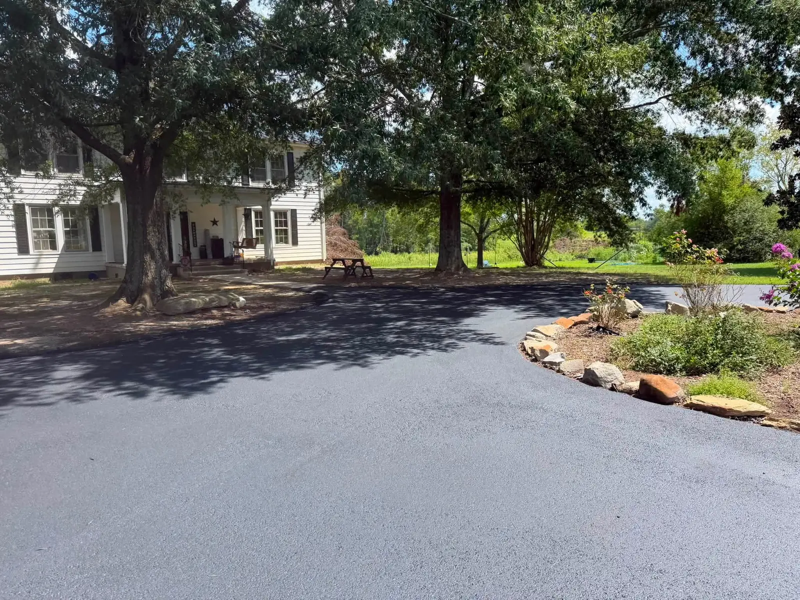 Finished circular asphalt driveway under mature trees
