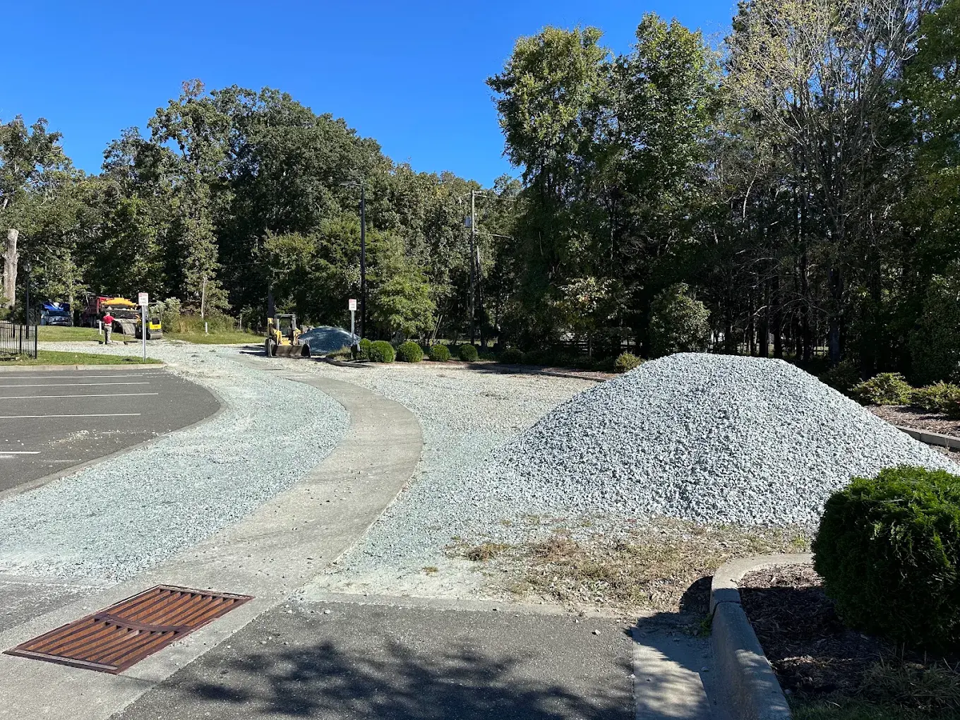 Crushed stone and a gravel stockpile beside a curved curb during base preparation