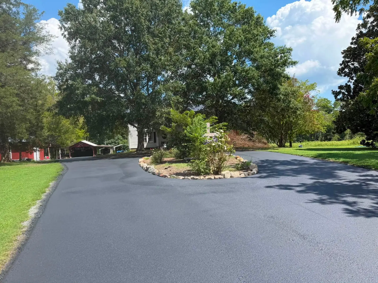 Smooth asphalt surrounding a landscaped island beneath a large tree